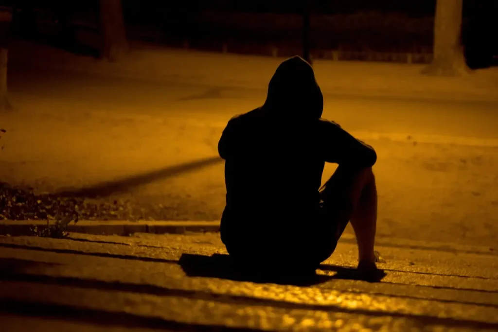 Person sitting alone in a park, contemplating sensitive issues